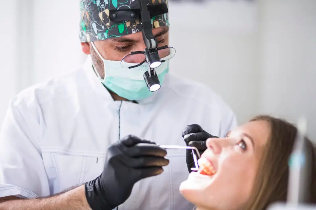 Dentist performing a dental check-up on a female patient, emphasizing professional care for maintaining dental implants and preventing complications like peri-implantitis.