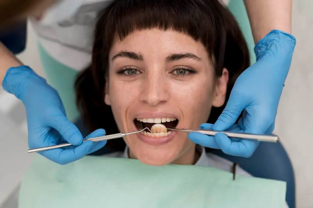 Female patient undergoing dental examination with instruments in mouth, highlighting the importance of dental procedures like ridge augmentation for implants.