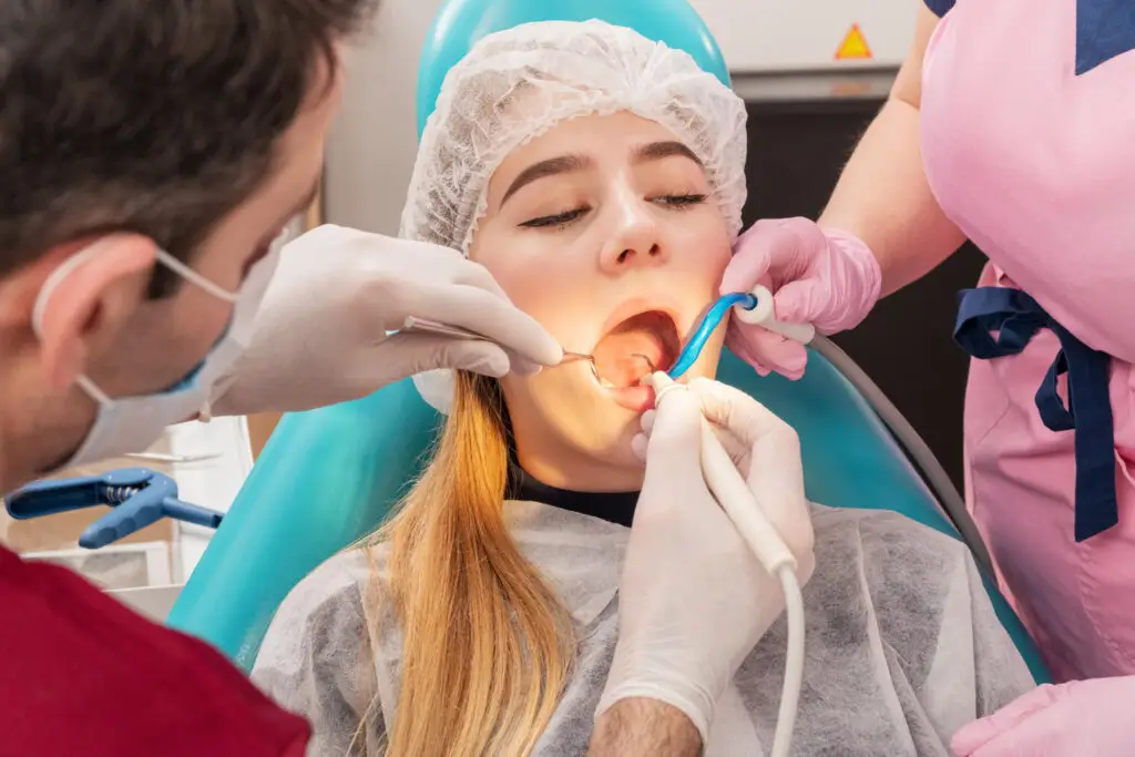 Dentist performing a surgical dental procedure on a patient during wisdom teeth removal.