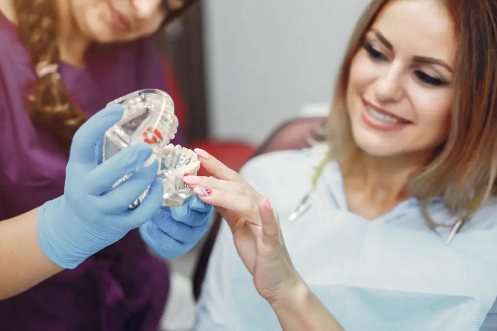 Patient discussing All-on-4 dental implants with a dental professional while examining a dental model.