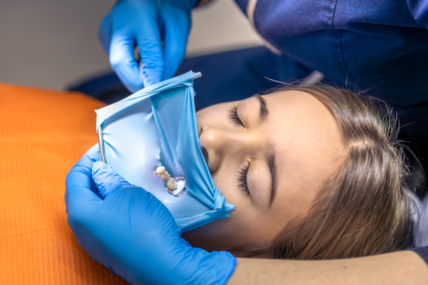 Patient receiving dental treatment with a dentist preparing the mouth for tooth extraction and bone grafting
