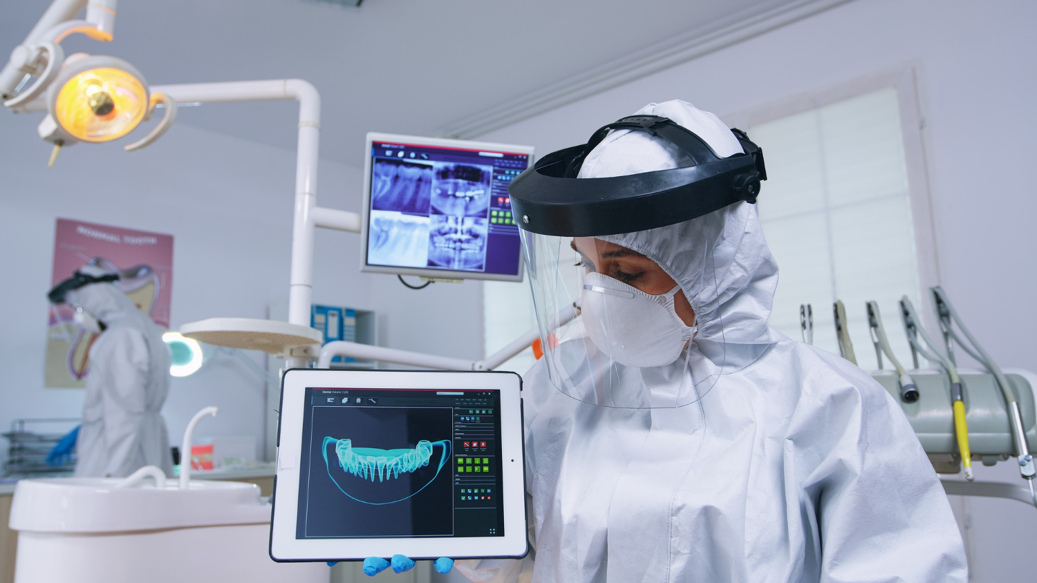 Dental professional reviewing a 3D digital teeth scan on a tablet in a modern dental clinic.