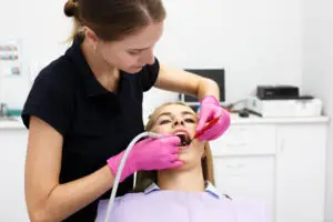 Dentist performing professional dental cleaning for a patient during a regular teeth cleaning appointment for gum health.