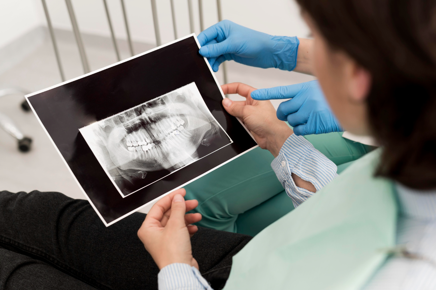 A dentist showing a patient a dental X-ray while explaining the findings during a dental consultation.